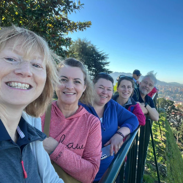 View of 5 crew members in the grounds of Vigo Castle gardens. Postioned in a line behind eachother along some railings. Dressed in casual clothes, smiling for the camera.