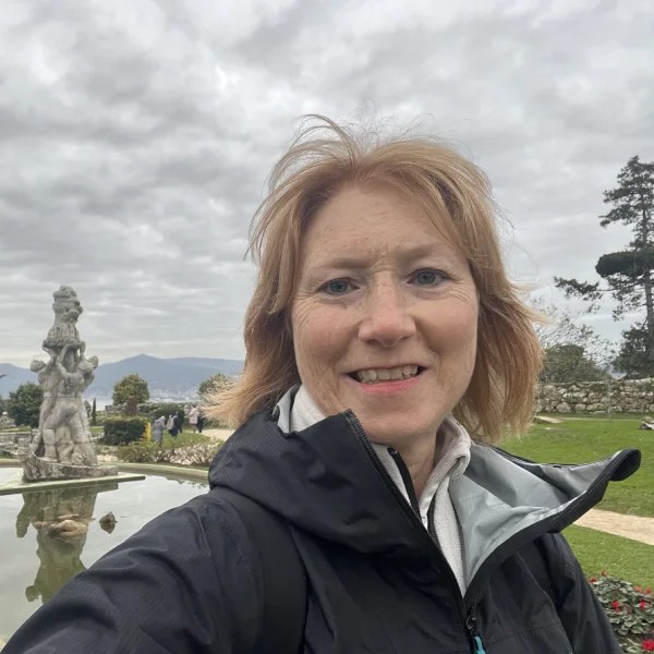 View of crew author and crew member at the top of vigo castle's gardens. Background is a view of beautiful statues and fountains amidst green gardens with pine trees. Distant views of Vigo's harbour.